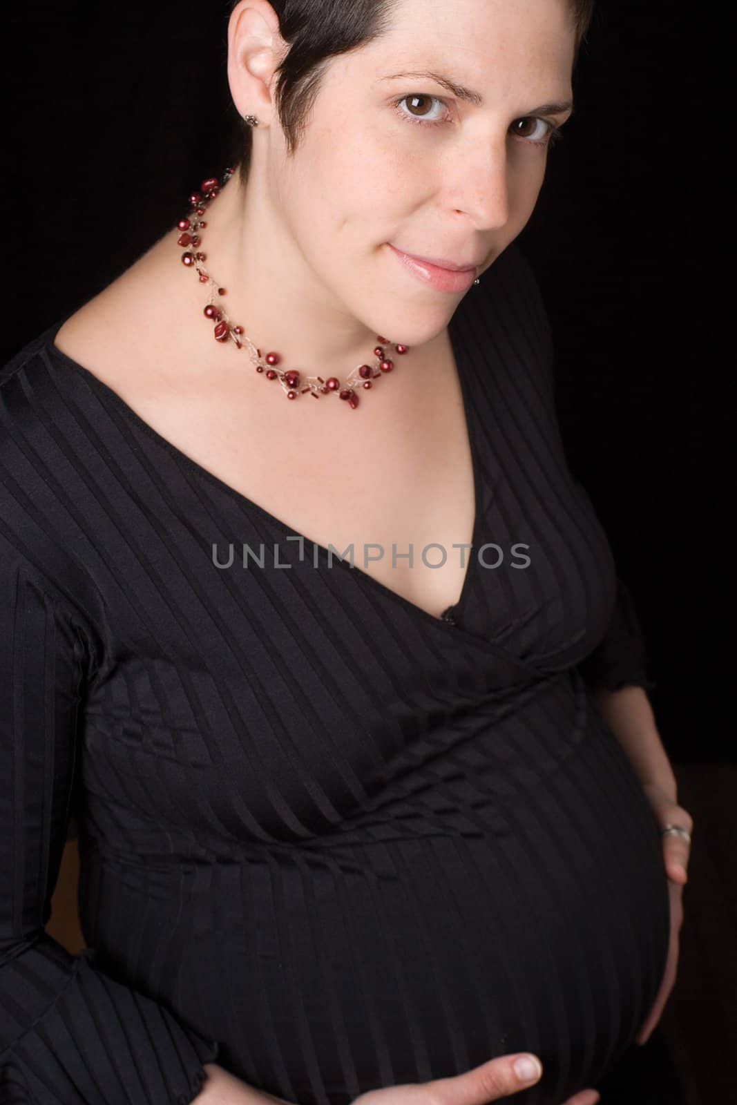 Portrait of a late twentie pregnant women looking at the camera with a shy smile