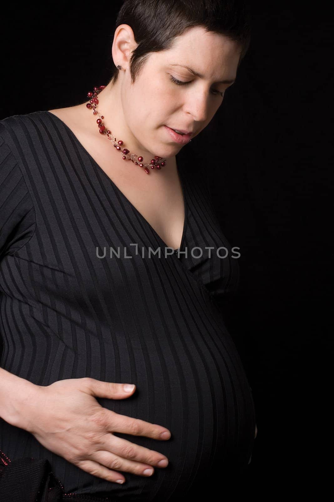 Late twentie pregnant woment looking at her belly with a perplexe expression