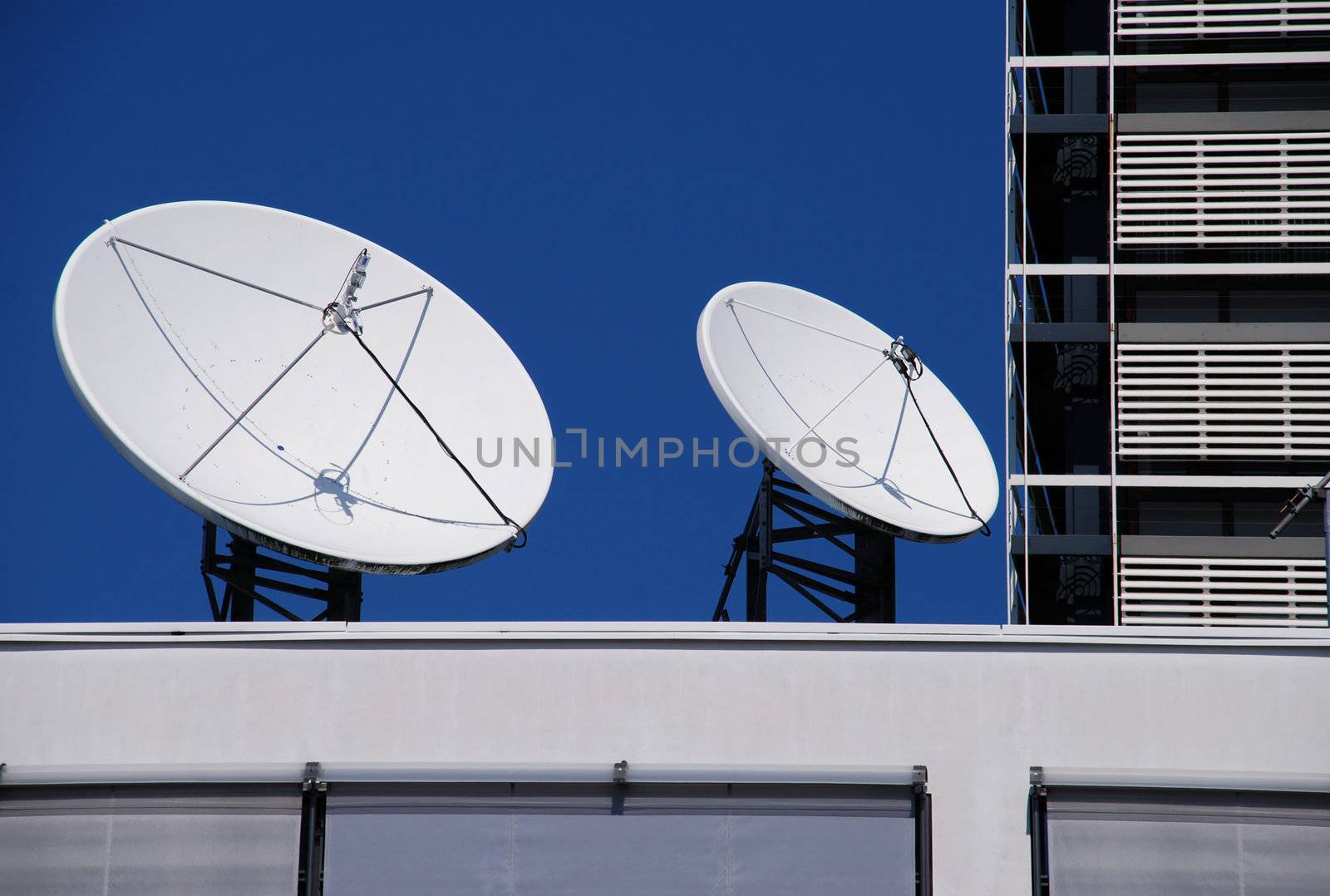 Couple of satellite dishes on roof, blue sky background