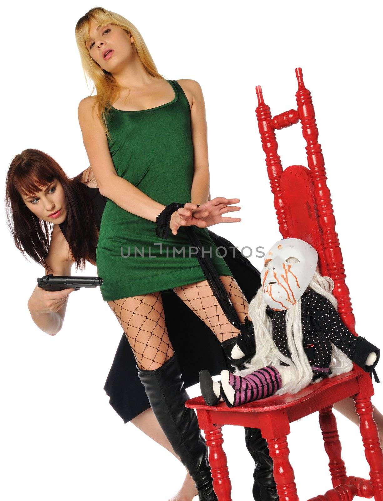 red head with a gun and a blonde tied to an evil little doll in a red chair