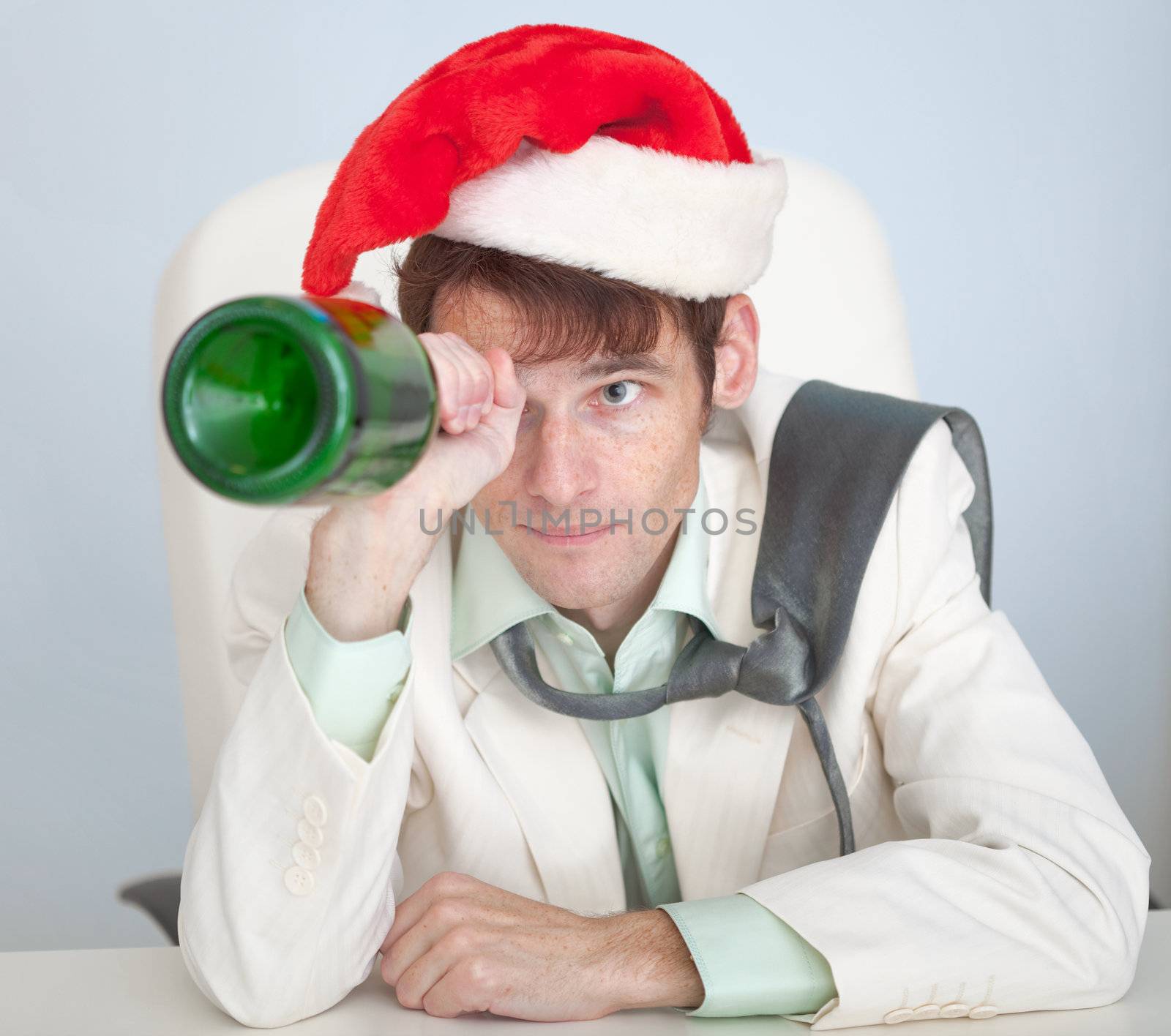 The drunk man in a Christmas cap plays with a bottle