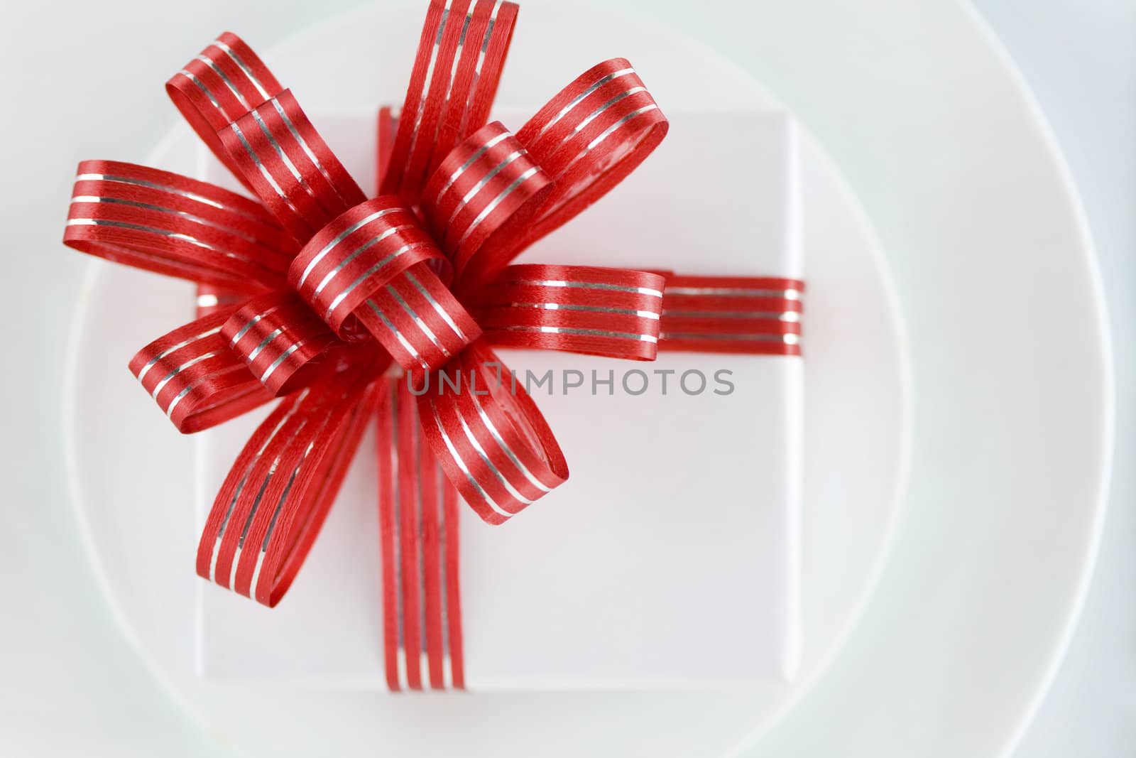 White present with red ribbons on a dinner plate, christmas theme