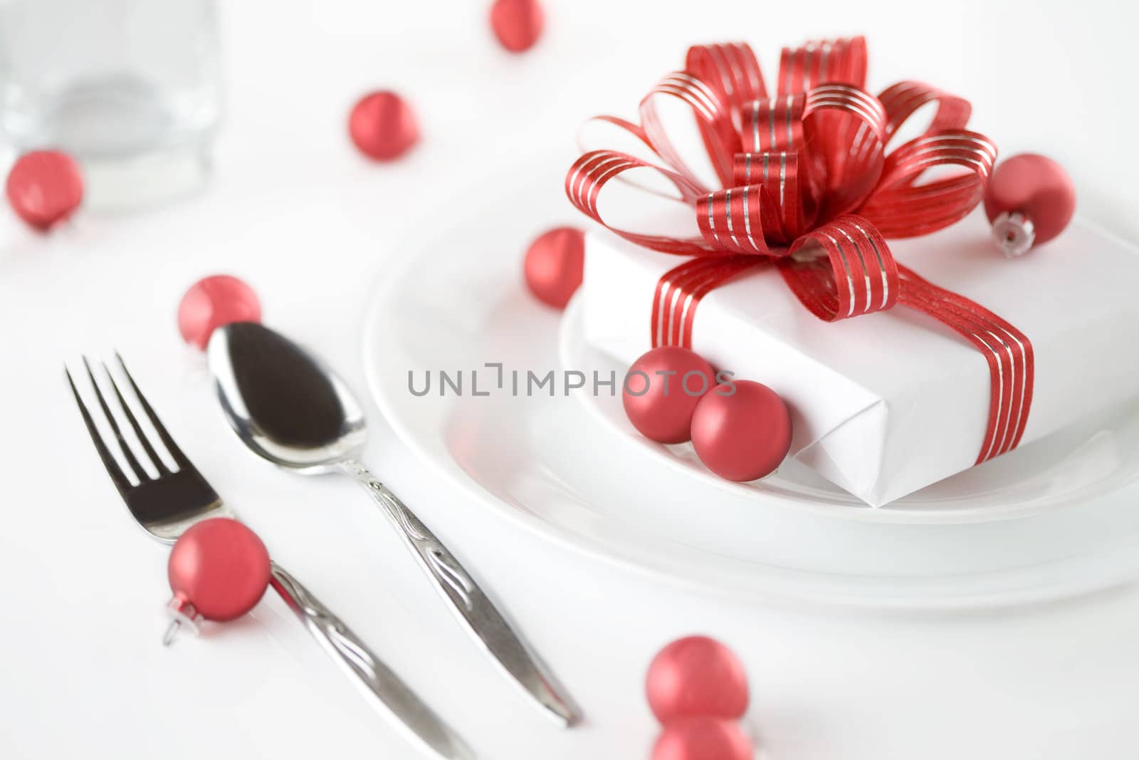 White present with red ribbons on a dinner plate and ornaments, christmas theme