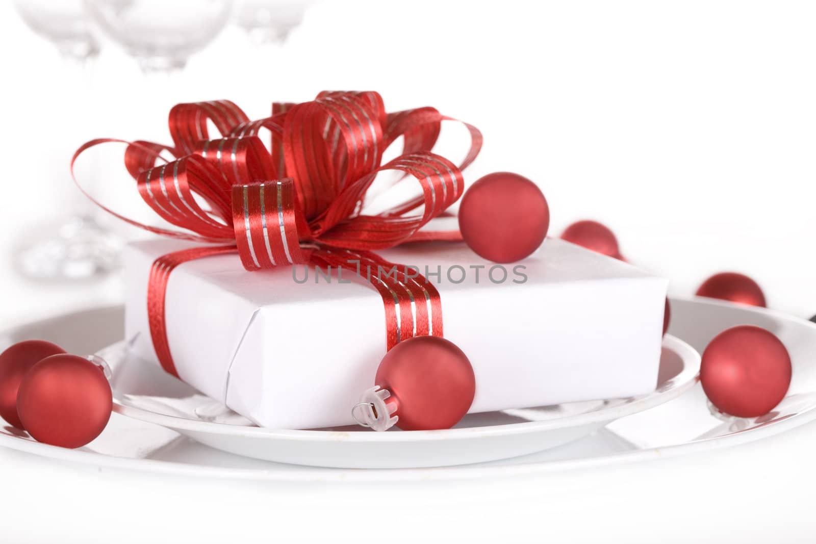 White present with red ribbons on a dinner plate by jarenwicklund
