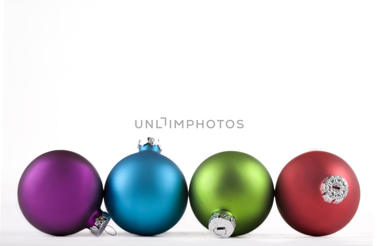 Blue  green,  red, and purple Christmas ornaments lined up, isolated