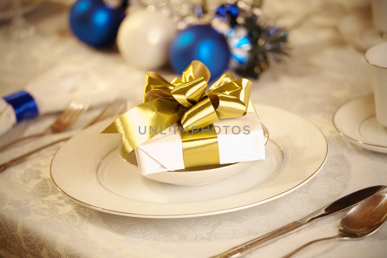 Elegant blue and white Christmas table setting with gold ribbon gift
