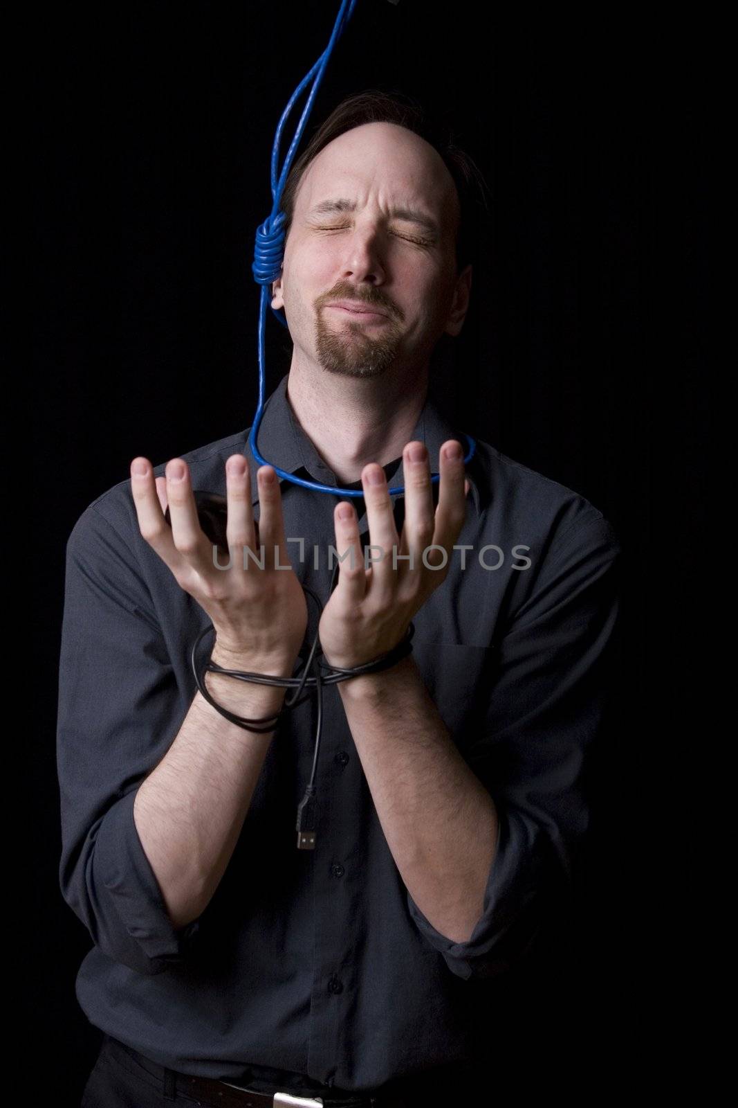 Computer technician with tied hands and hangman noeuce around his neck, pleading for mercy