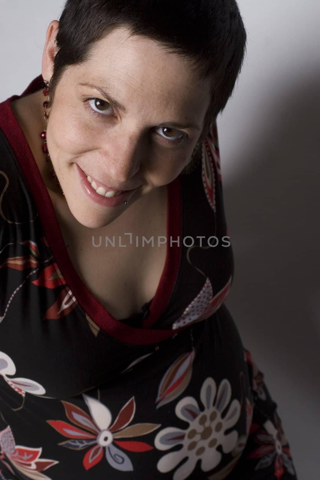 Late twenties pregnant women with boyish look on white seamless sitting on ground level