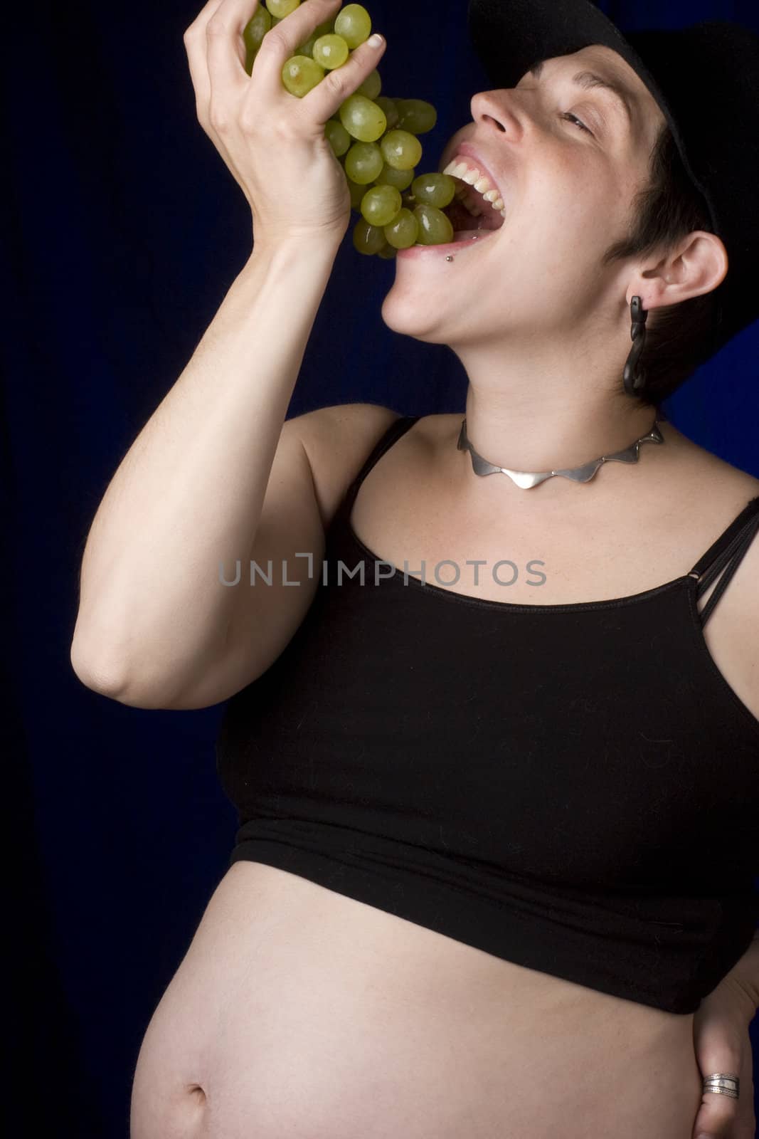 Twenty something pregnant women with boyish look eating green grapes
