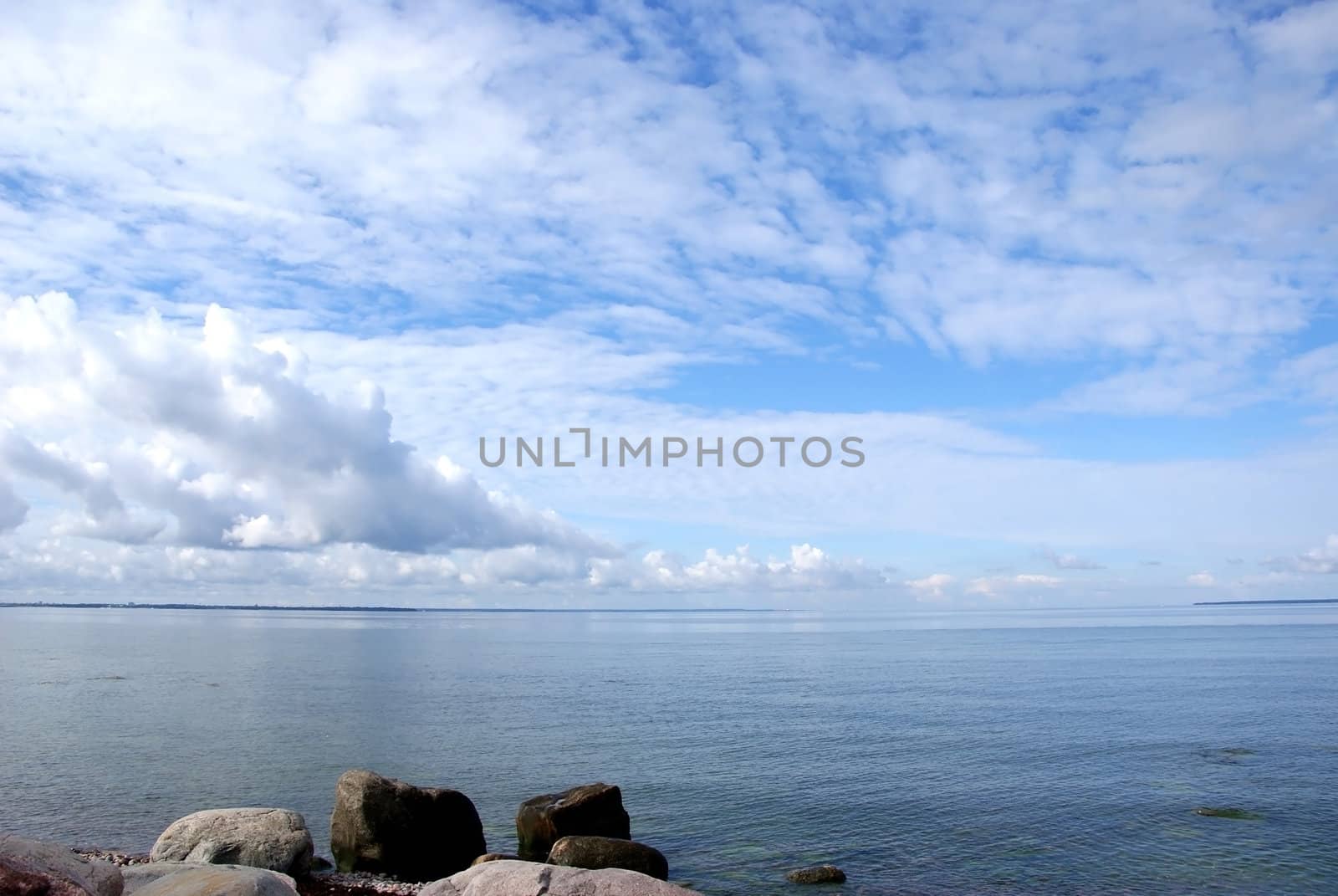 The sea on a background of the blue sky and clouds