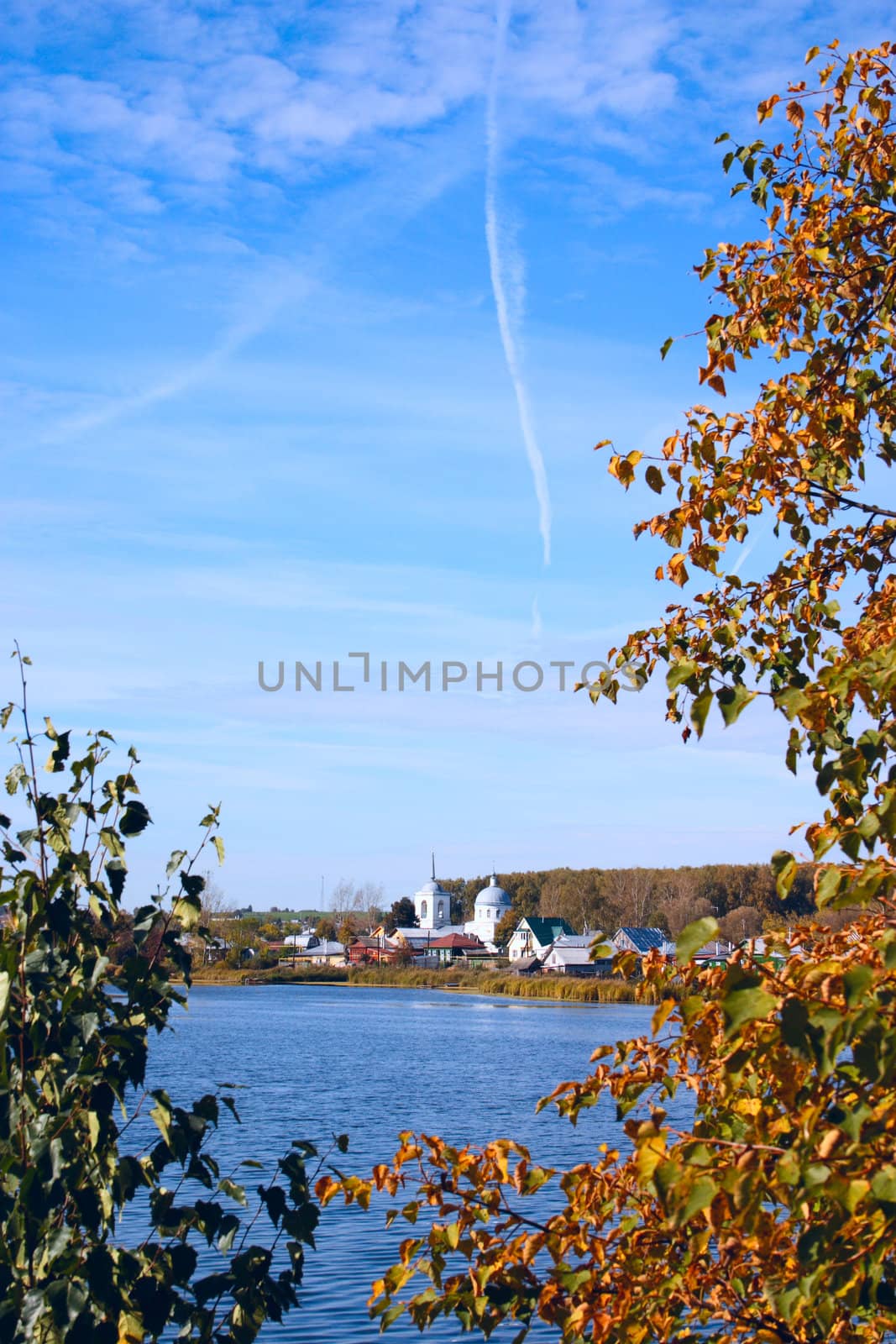 Autumn lake with a kind on village removed through vegetation