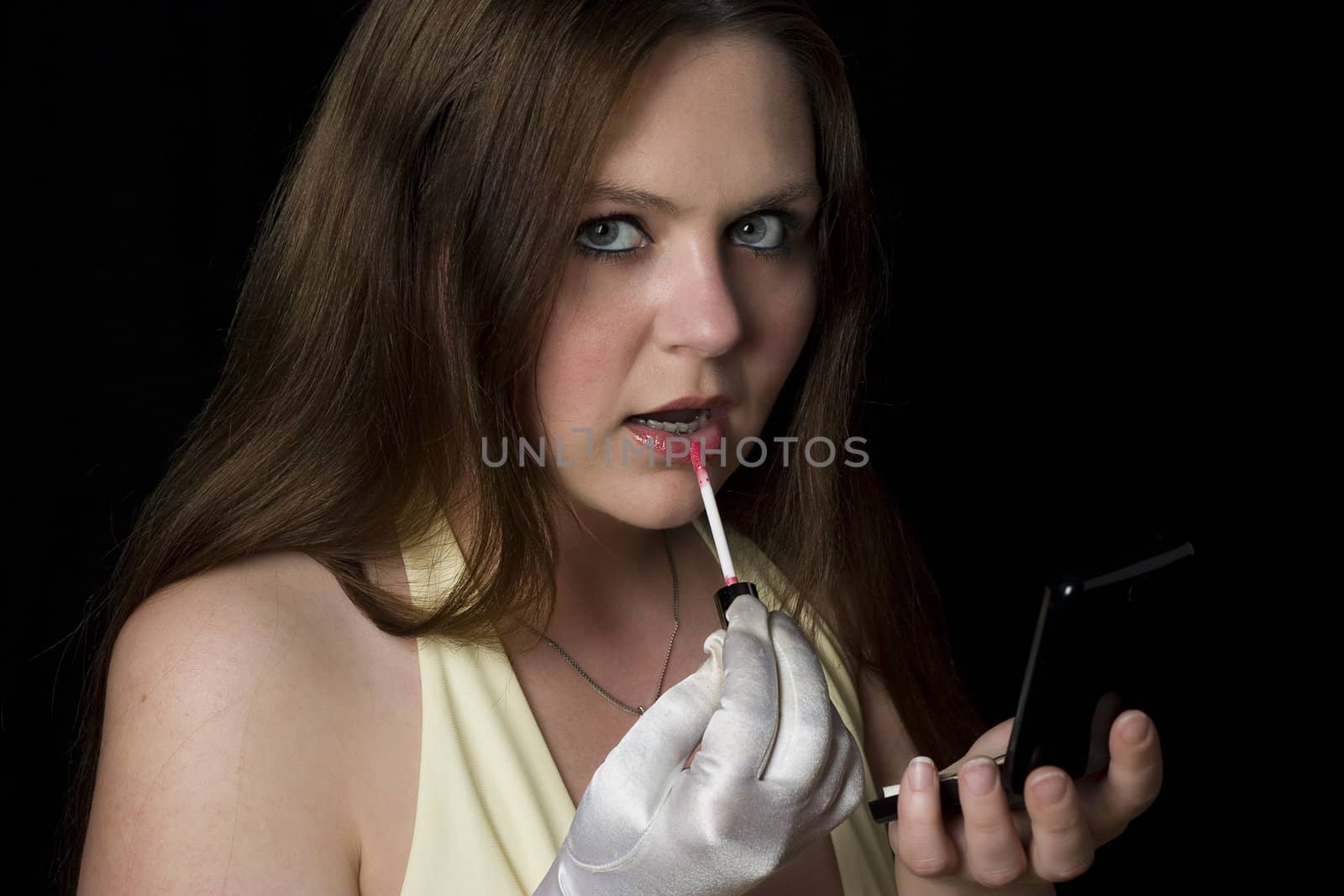 Twenty something girl in yellow evening dress applying makeup