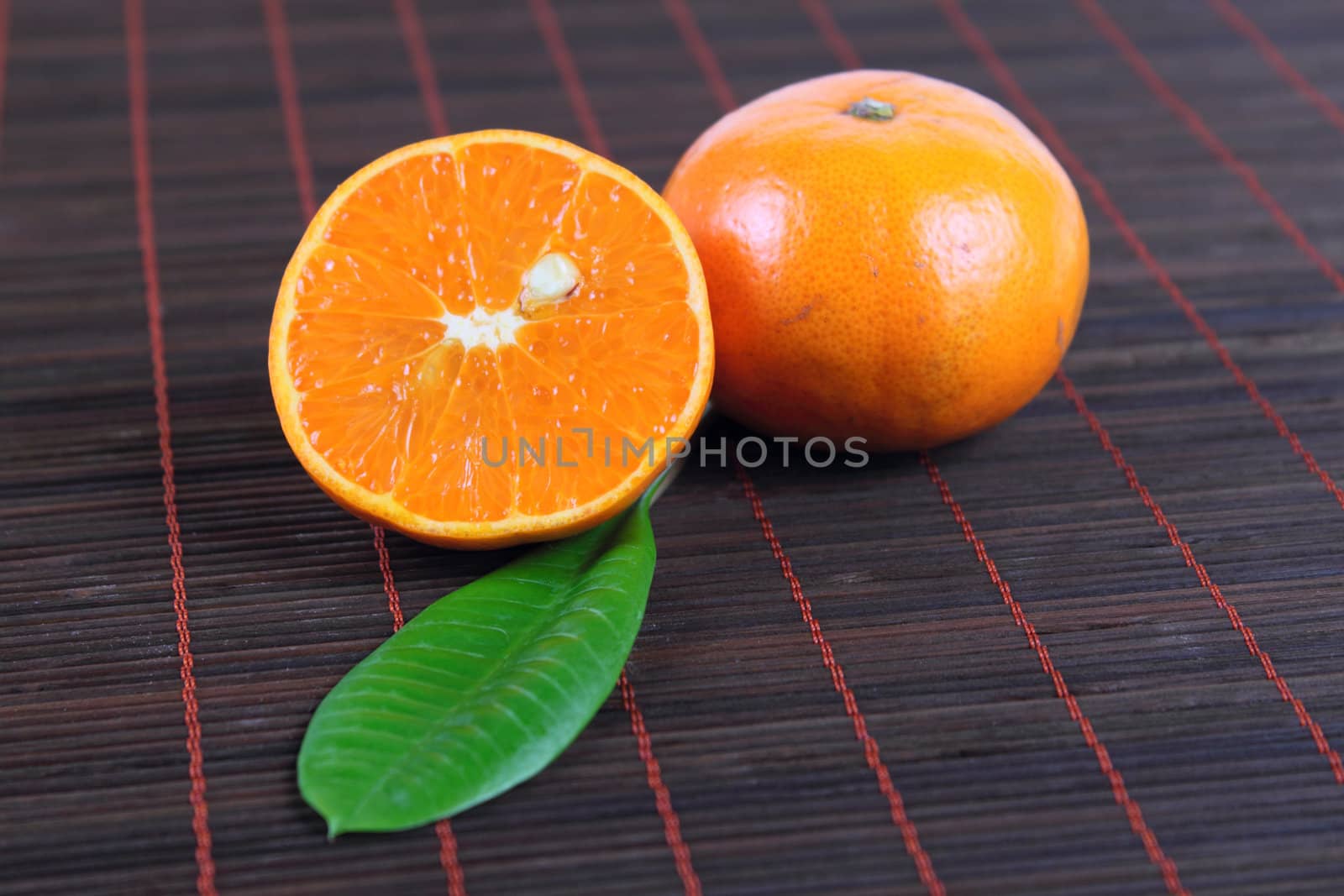 Two tangerines on a bamboo napkin with green sheet removed close up