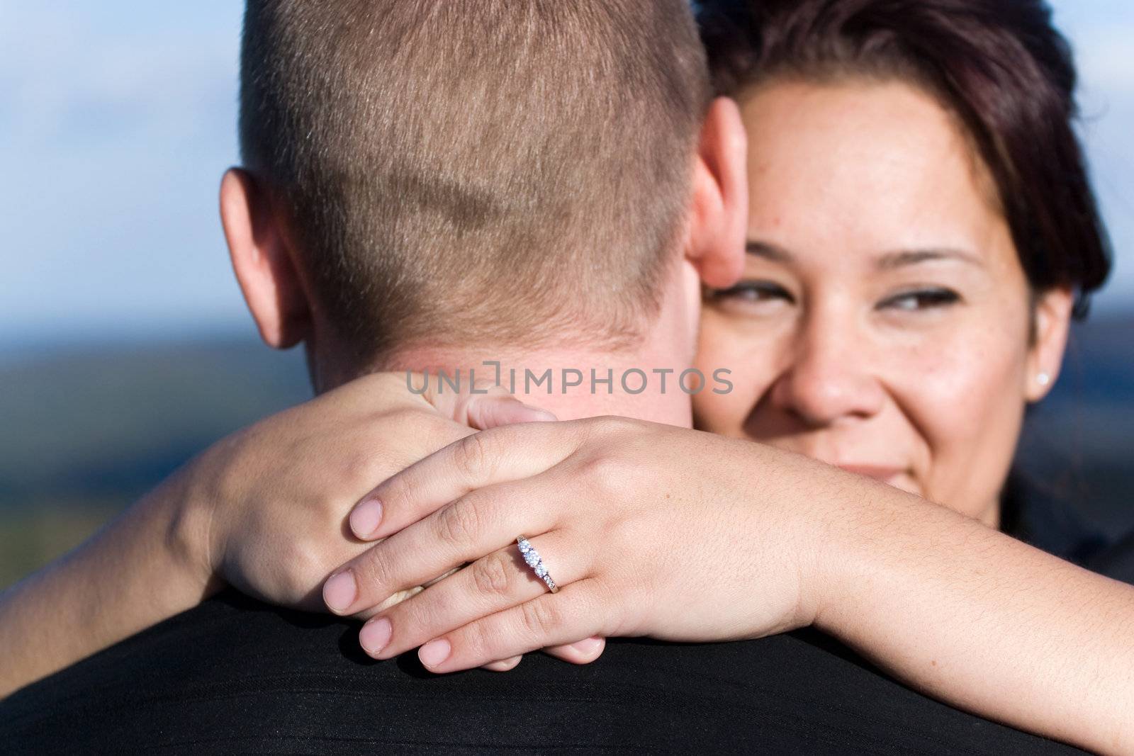 A young happy couple that just got engaged.  Shallow depth of field with focus on the diamond engagement ring.