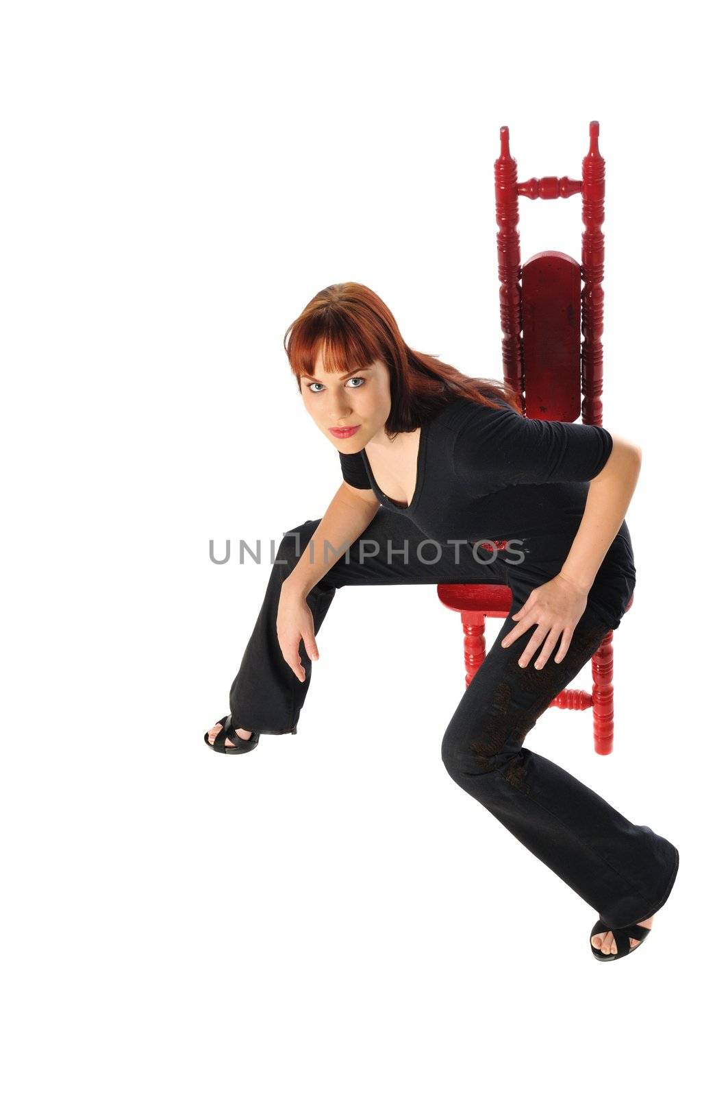 attractive redhead sitting in a red chair on a white background