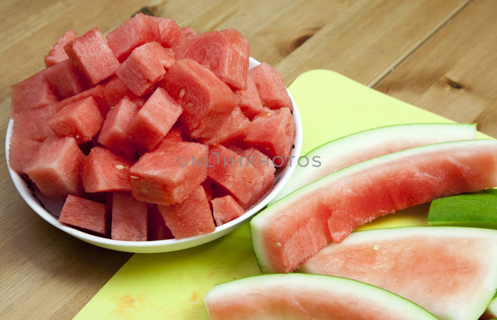 A bowl of freshly cut watermelon next to the rind