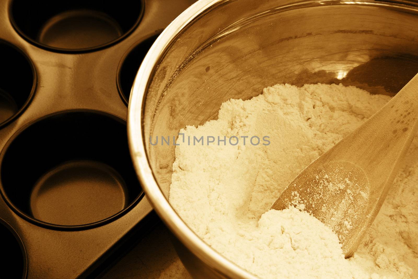Muffin ingredients in a mixing bowl next to a baking tray before cooking.