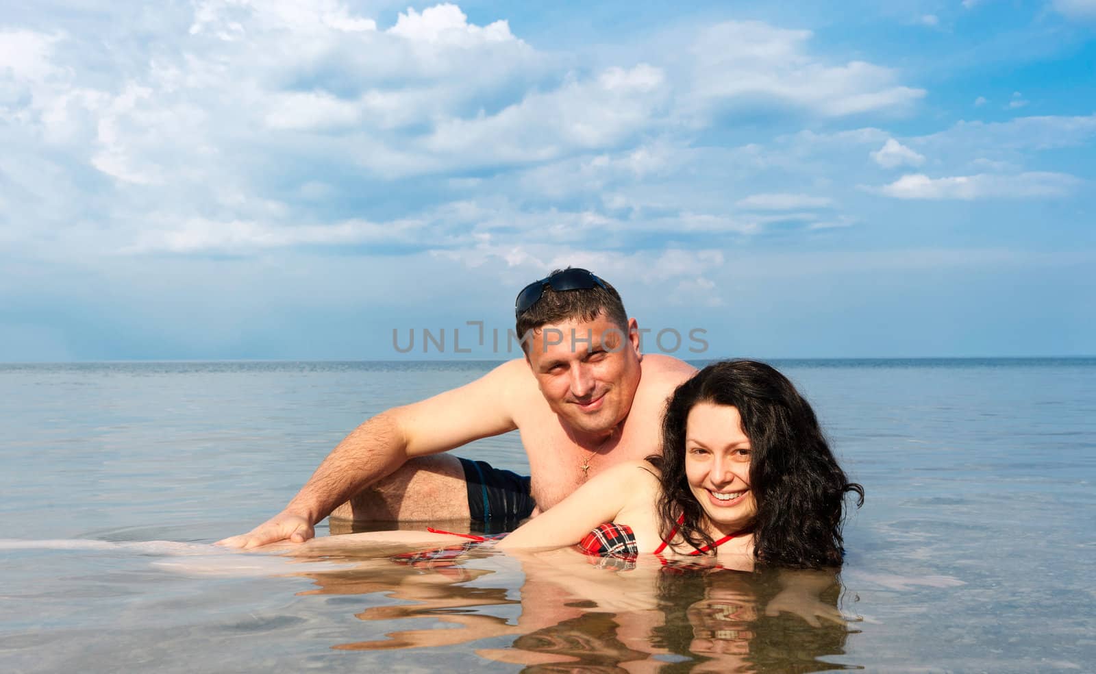 Young pair in the sea. Against the blue sky