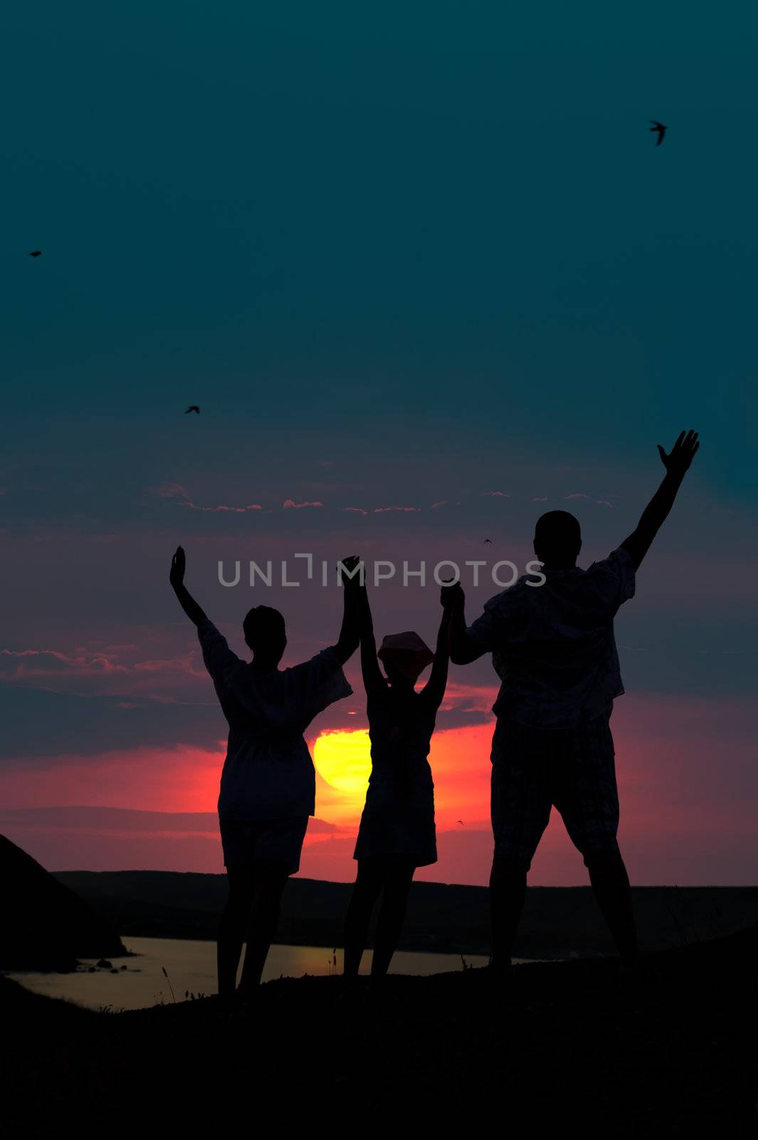 The family from three persons welcomes the sunset sun by galdzer