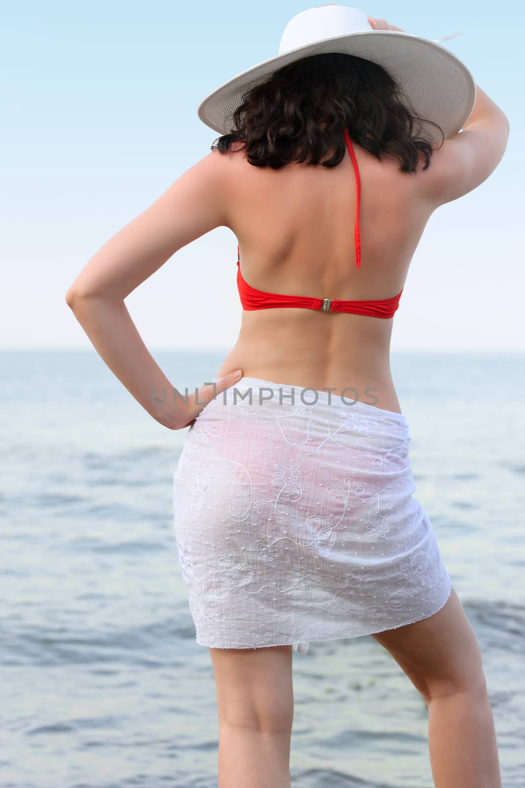 The woman on sea coast in a hat. The rear view