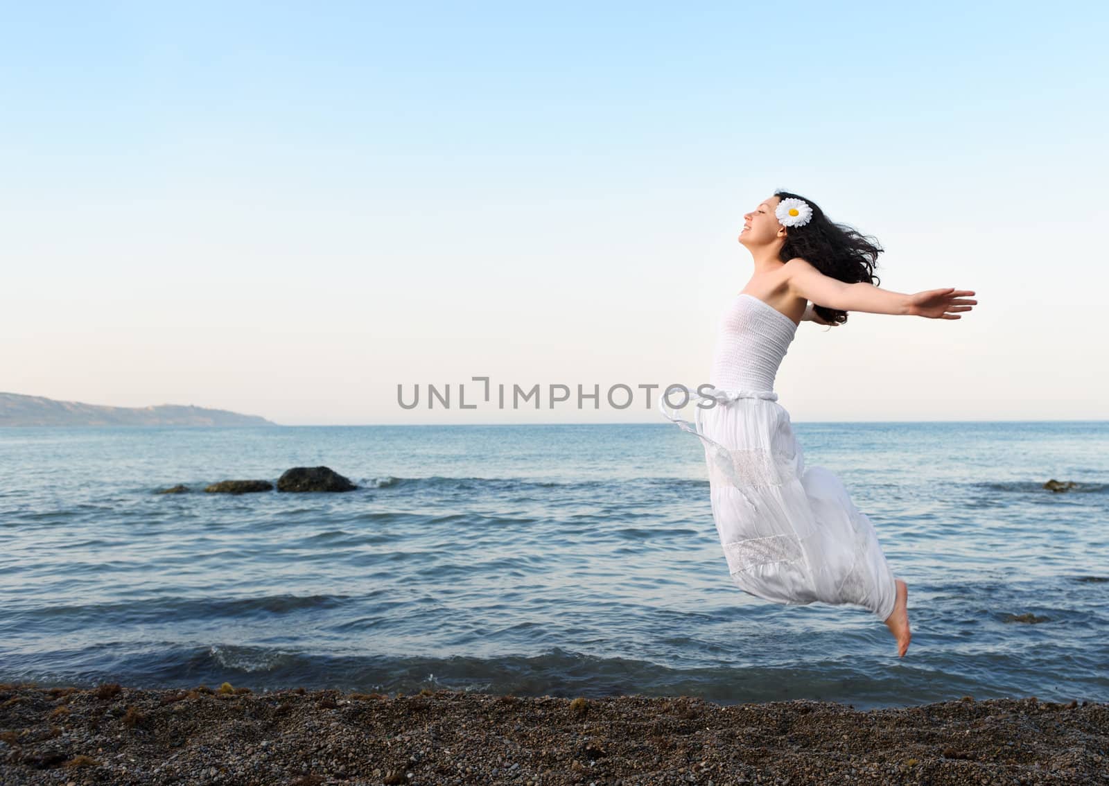 The young woman jumps on seacoast. A picturesque landscape