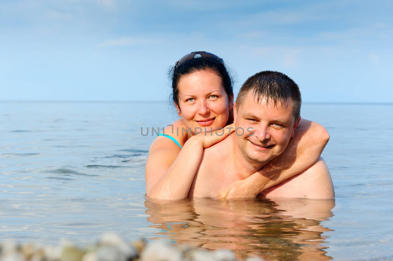 Happy young couple in the sea. Lie in water