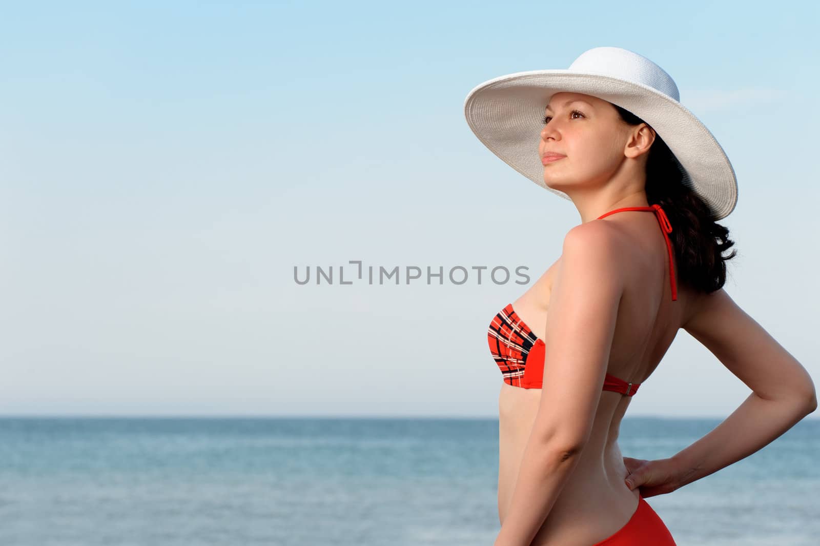 The girl in a hat against the sea and blue sky