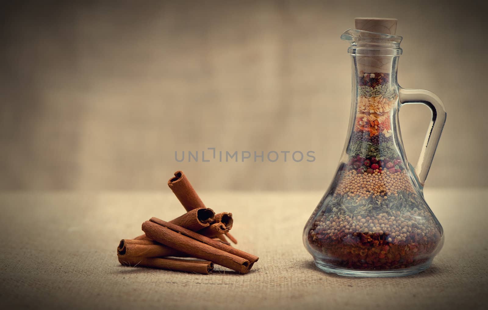 Bottle of spices and cinnamon. Capacity with a set of various spices and cinnamon on a rough background
