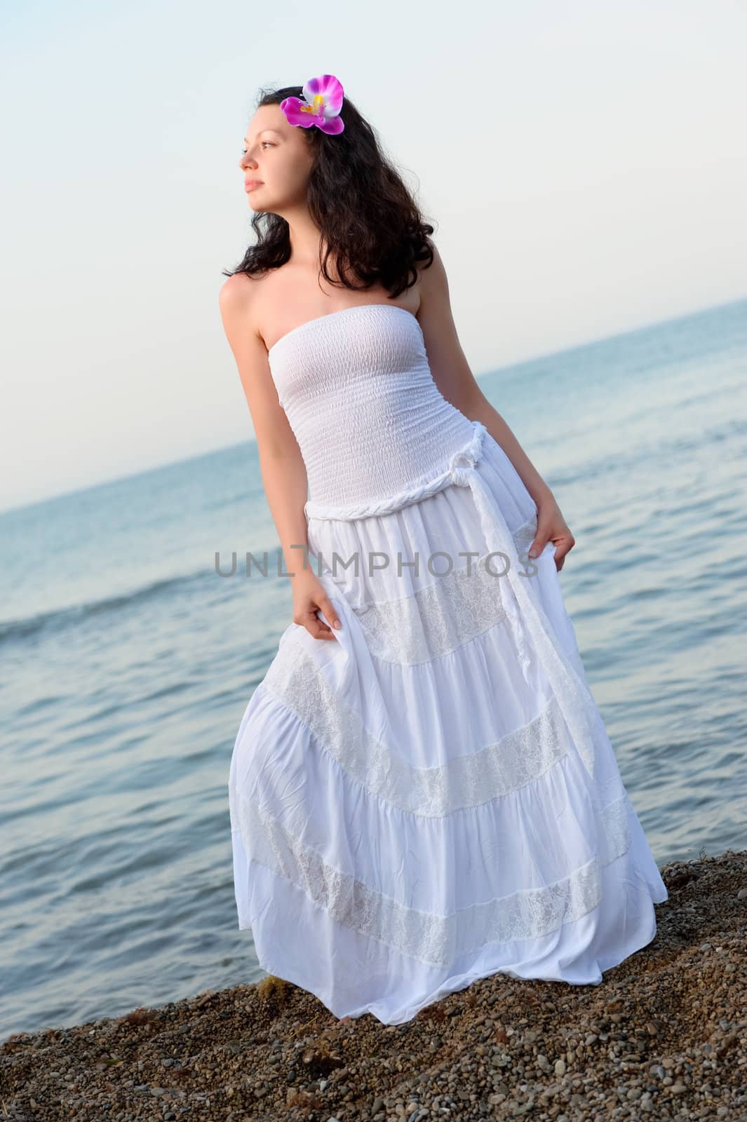 The woman in a white sundress on seacoast. A picturesque landscape