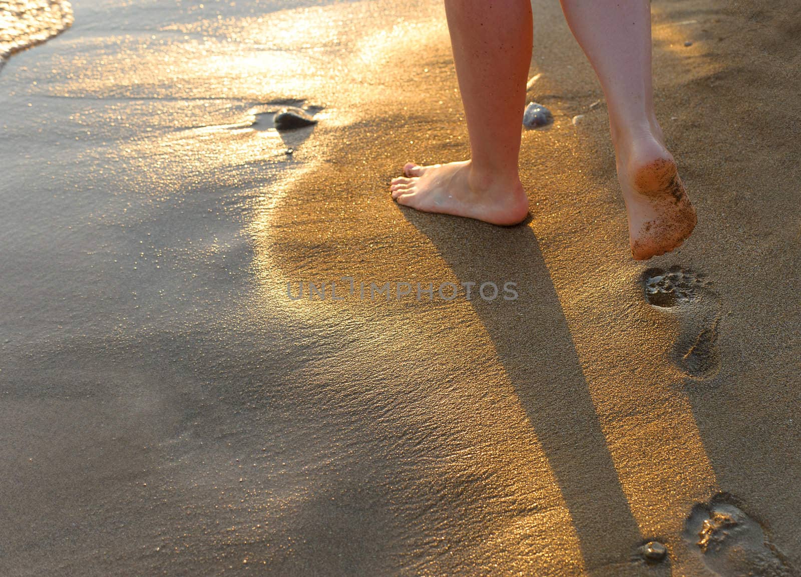 footprint on sand. Sunset illumination, a fragment of female feet