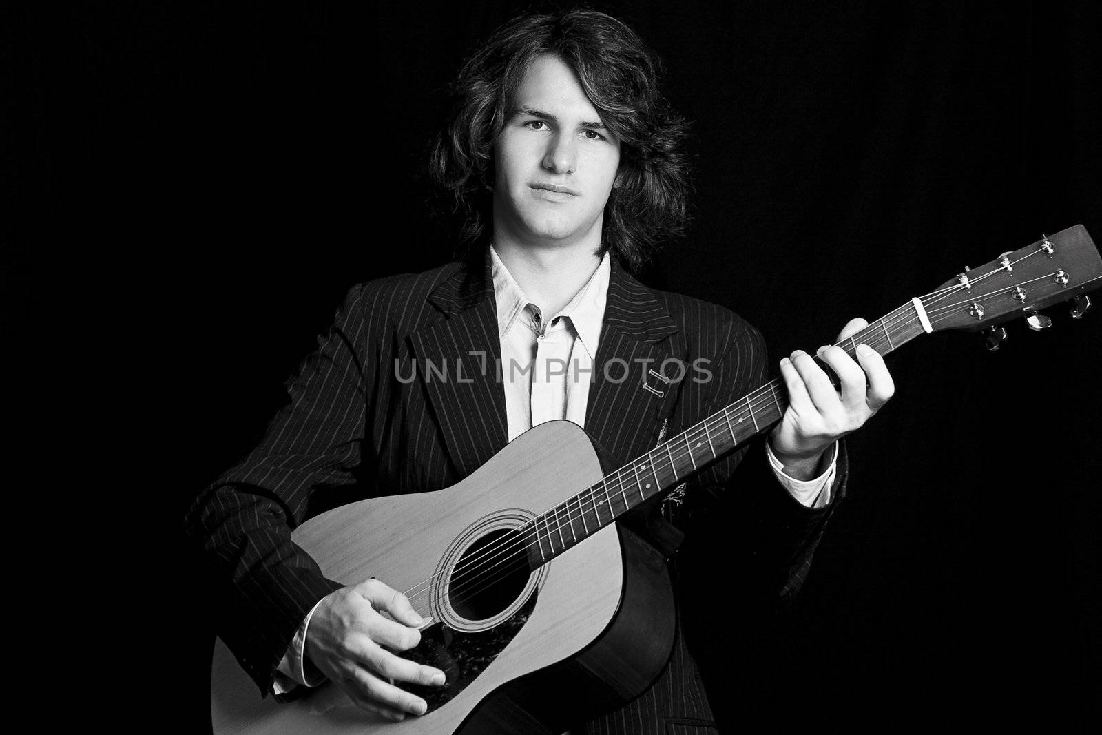 Male teenager folk guitar player with blank expression