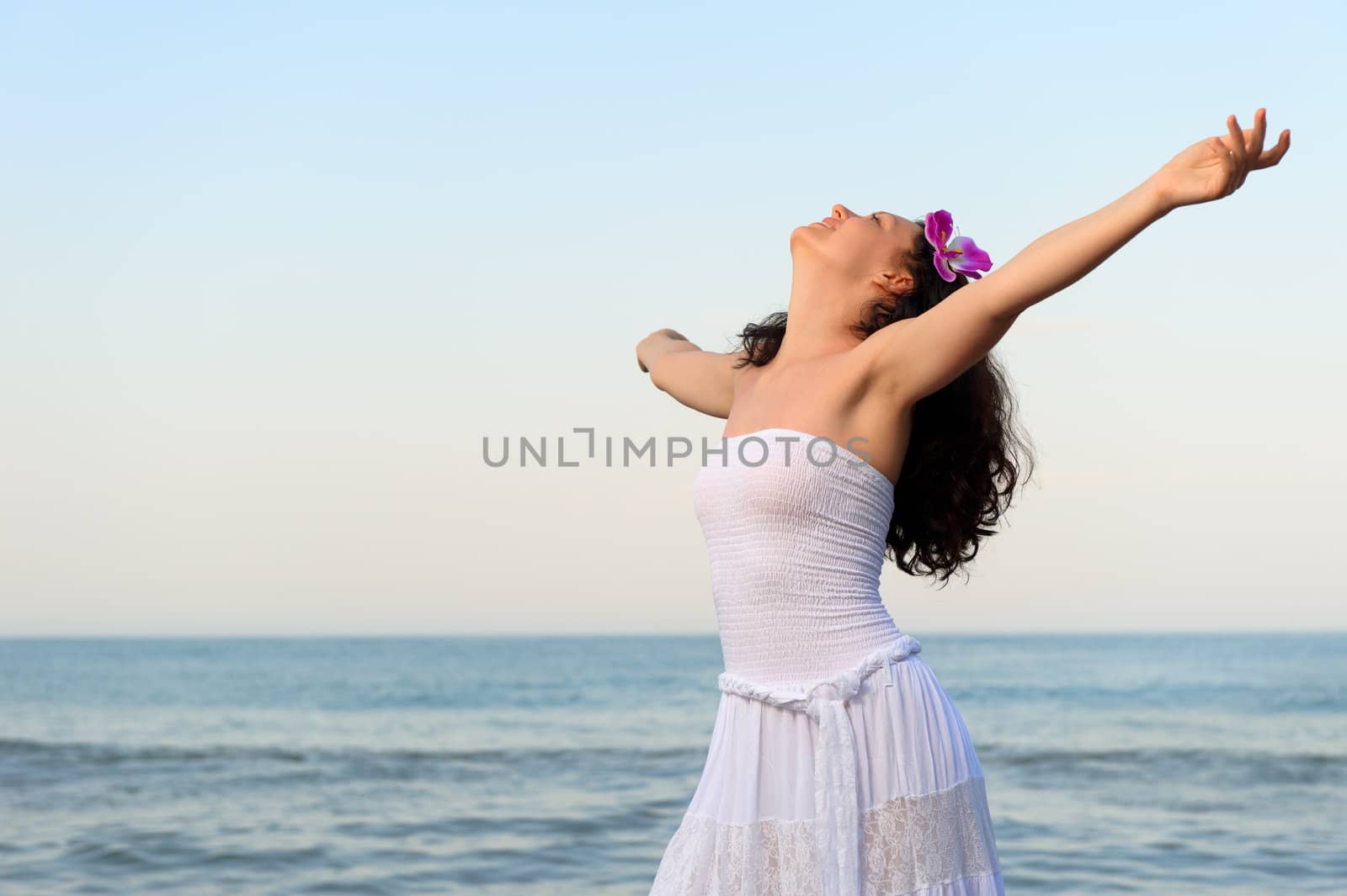 The woman in a white sundress on seacoast with open hands. A picturesque landscape