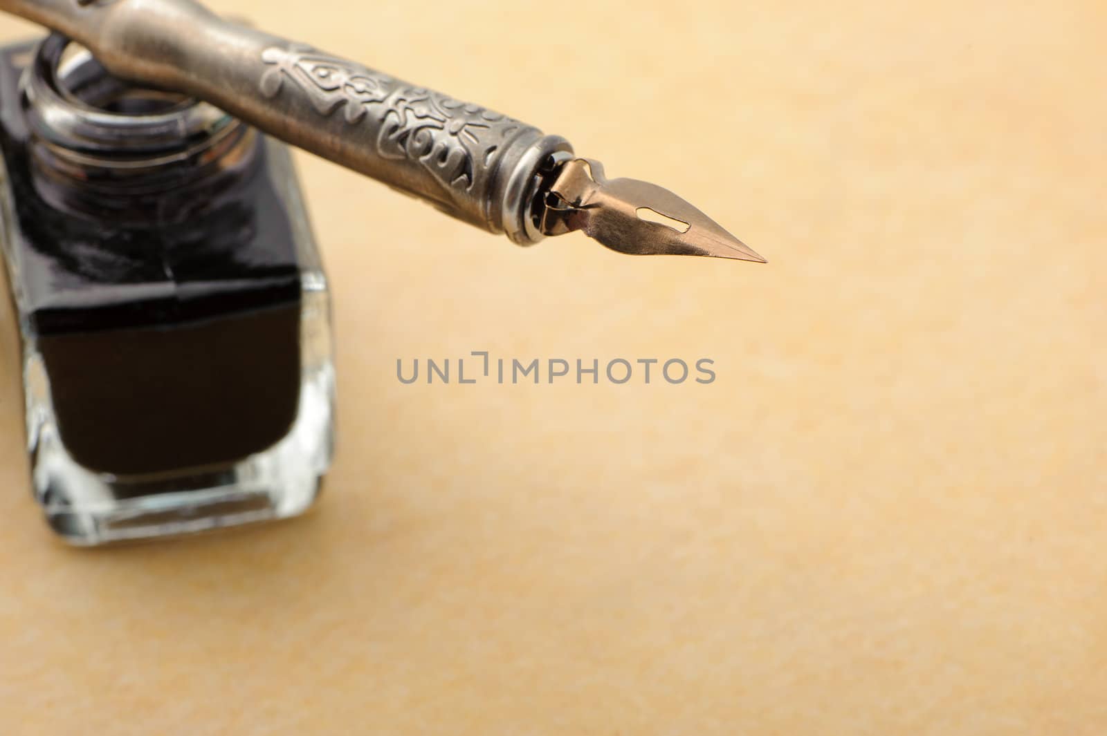 Feather quill and inkwell on an old paper. Photo closeup