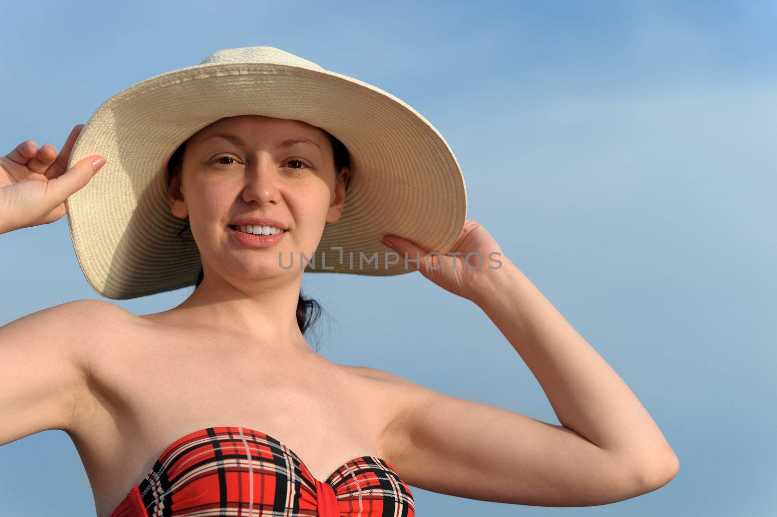 The girl in a hat against the blue sky