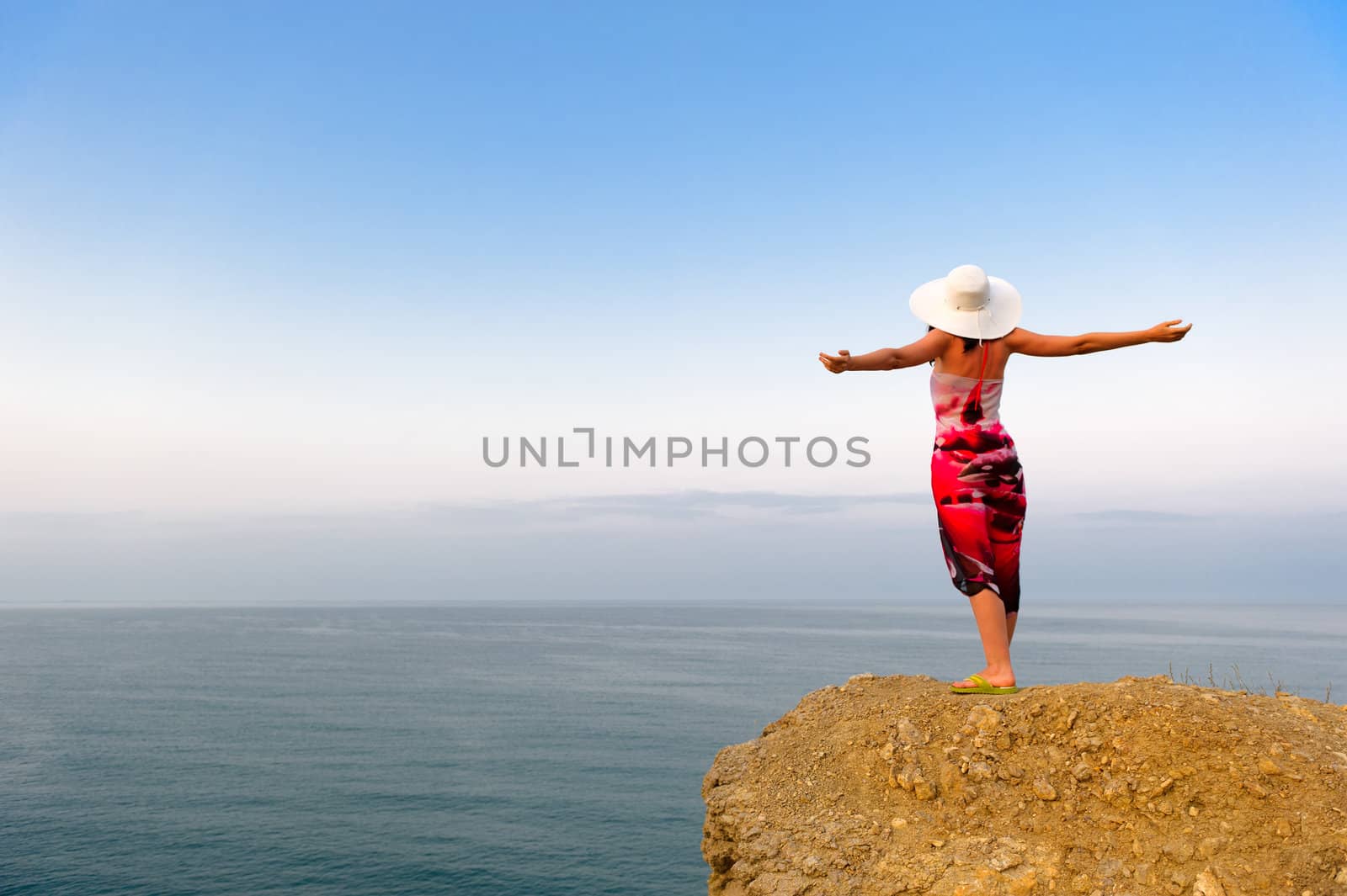 The woman on a mountain with open hands, against the blue sky by galdzer