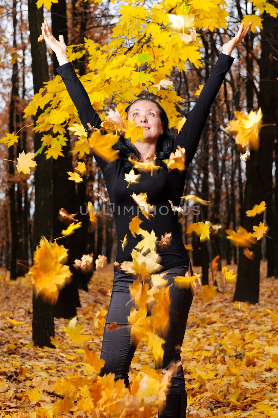 The women with the lifted hands autumn forest. Falling yellow leaf