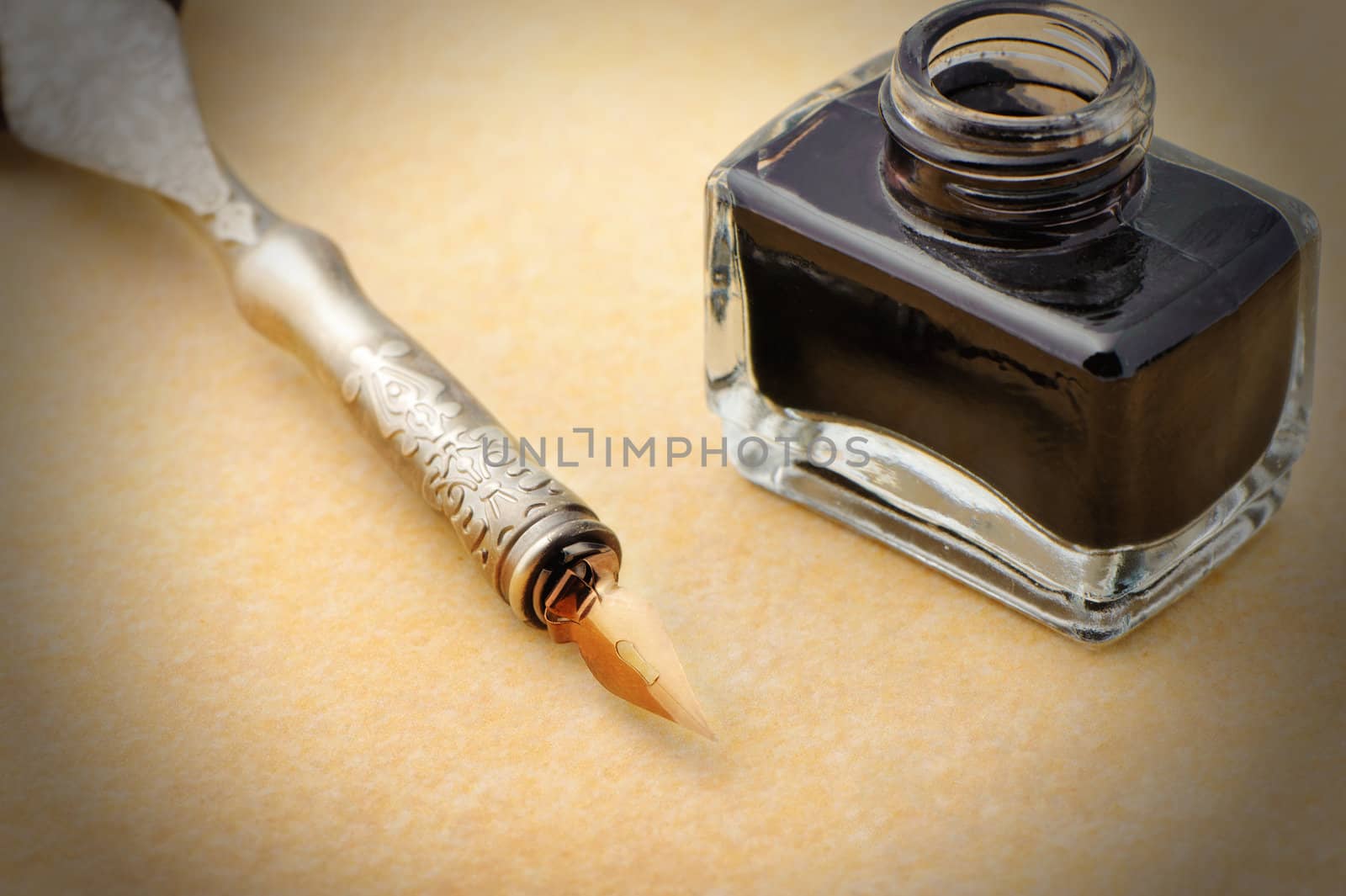 Feather quill and inkwell on an old paper. Photo closeup