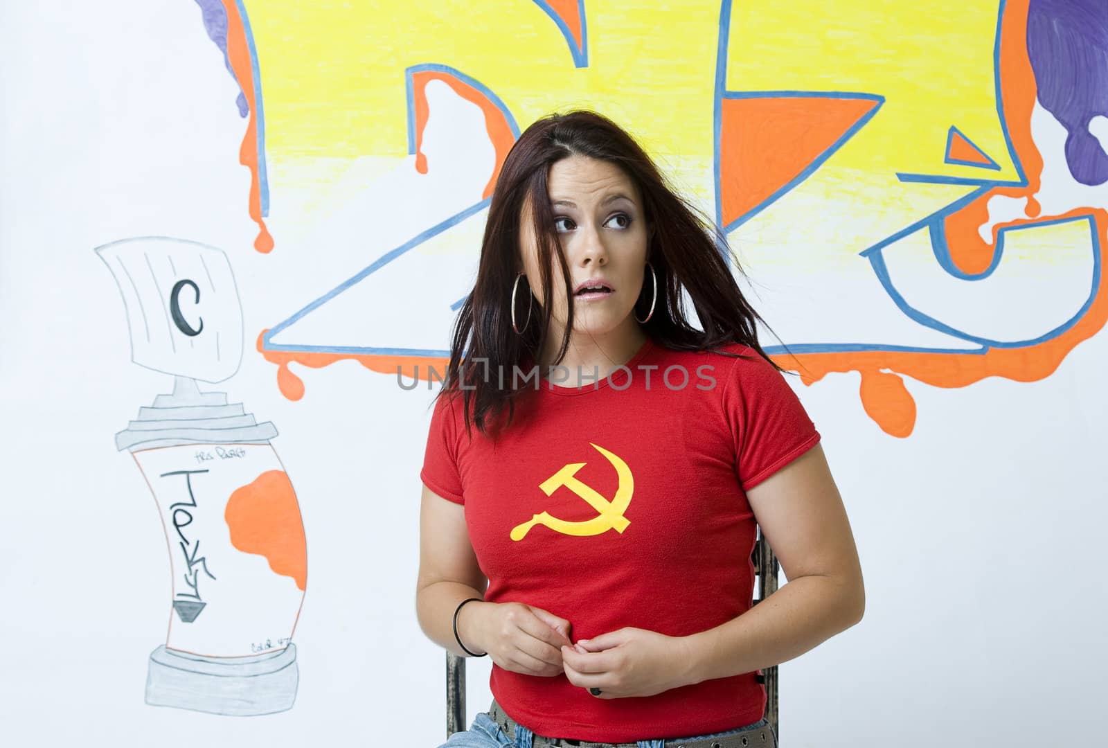 Young women with frighten expression sitting on a ruff up chair in front of a graffiti background