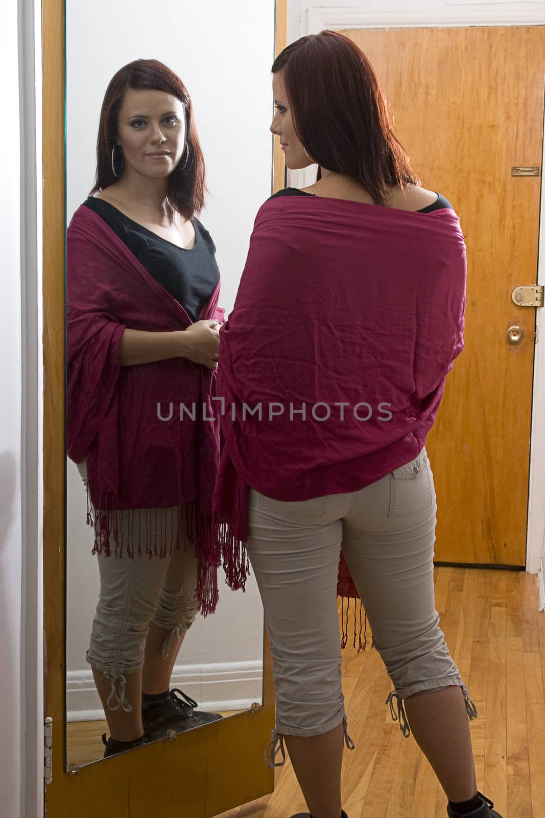 Young woman standing in front of mirror adjusting shawl