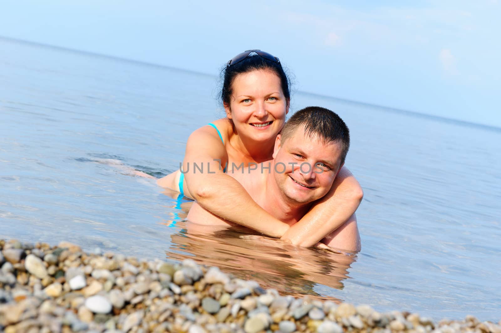 Happy young couple in the sea by galdzer