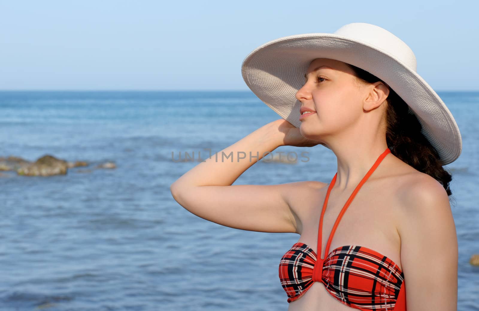 The girl in a hat against the sea and blue sky