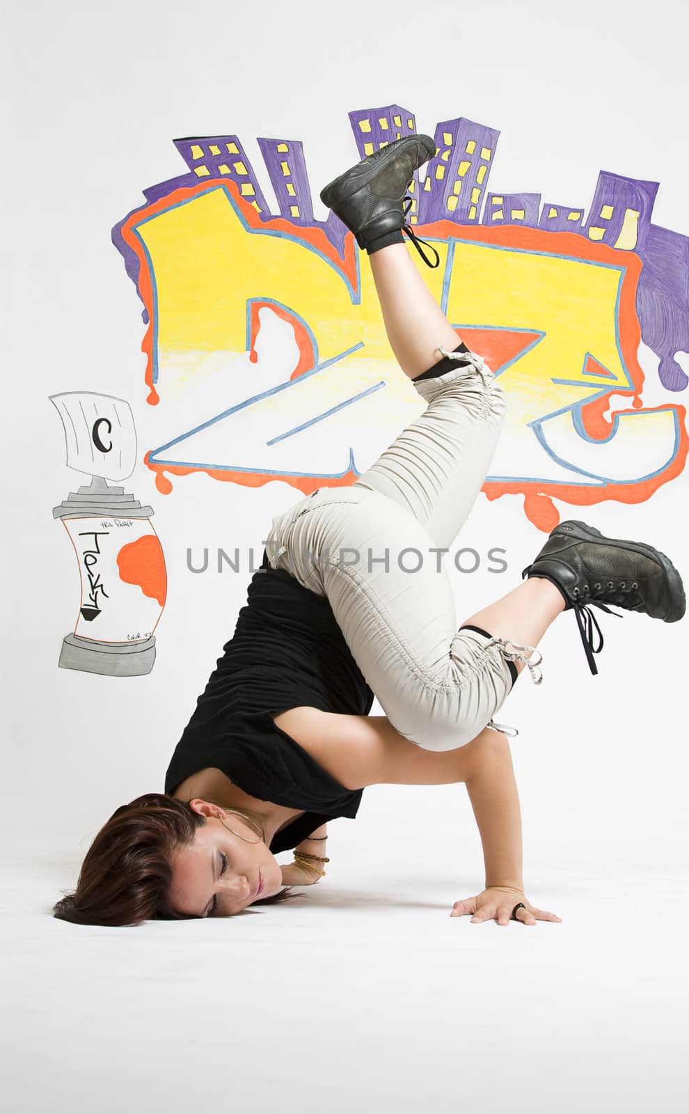 young women in the middle of a breakdancing move balancing on her head done in front of a graffiti background