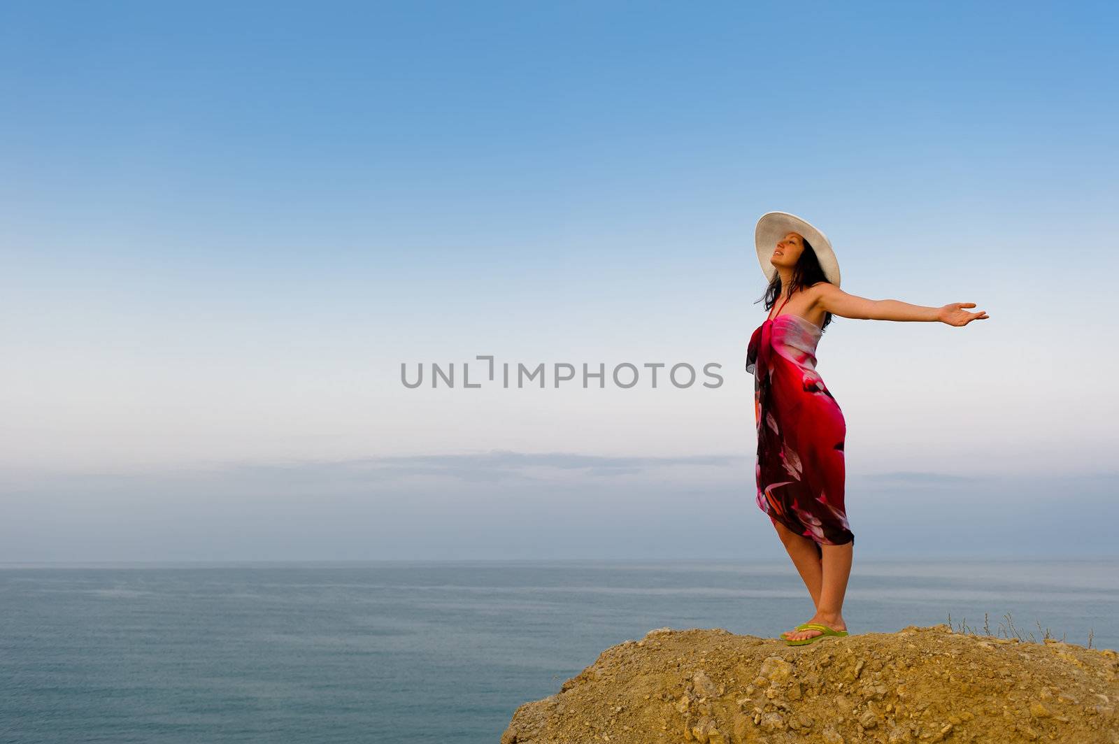 The woman on a mountain with open hands, against the blue sky