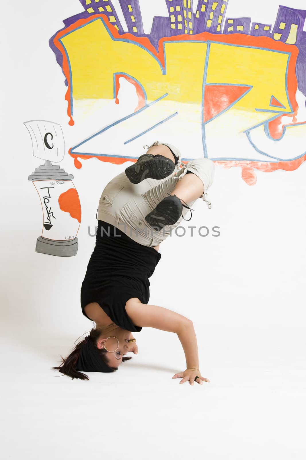 young women in the middle of a breakdancing move balancing on her head done in front of a graffiti background