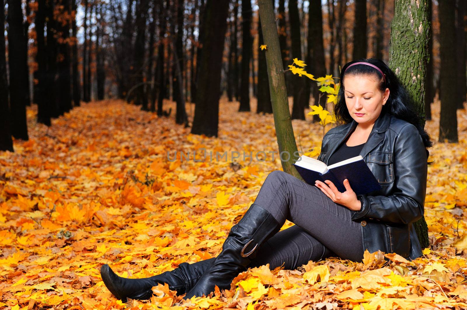 The attractive woman reads the book in autumn forest by galdzer