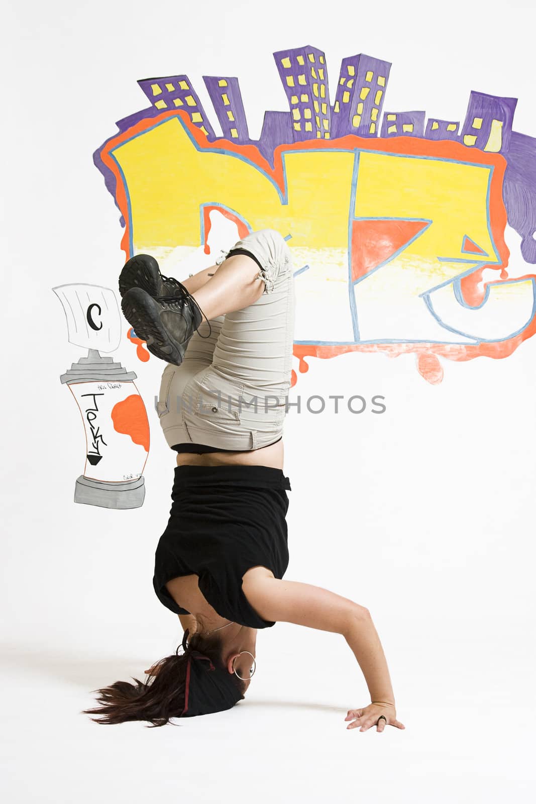 young women in the middle of a breakdancing move balancing on her head done in front of a graffiti background