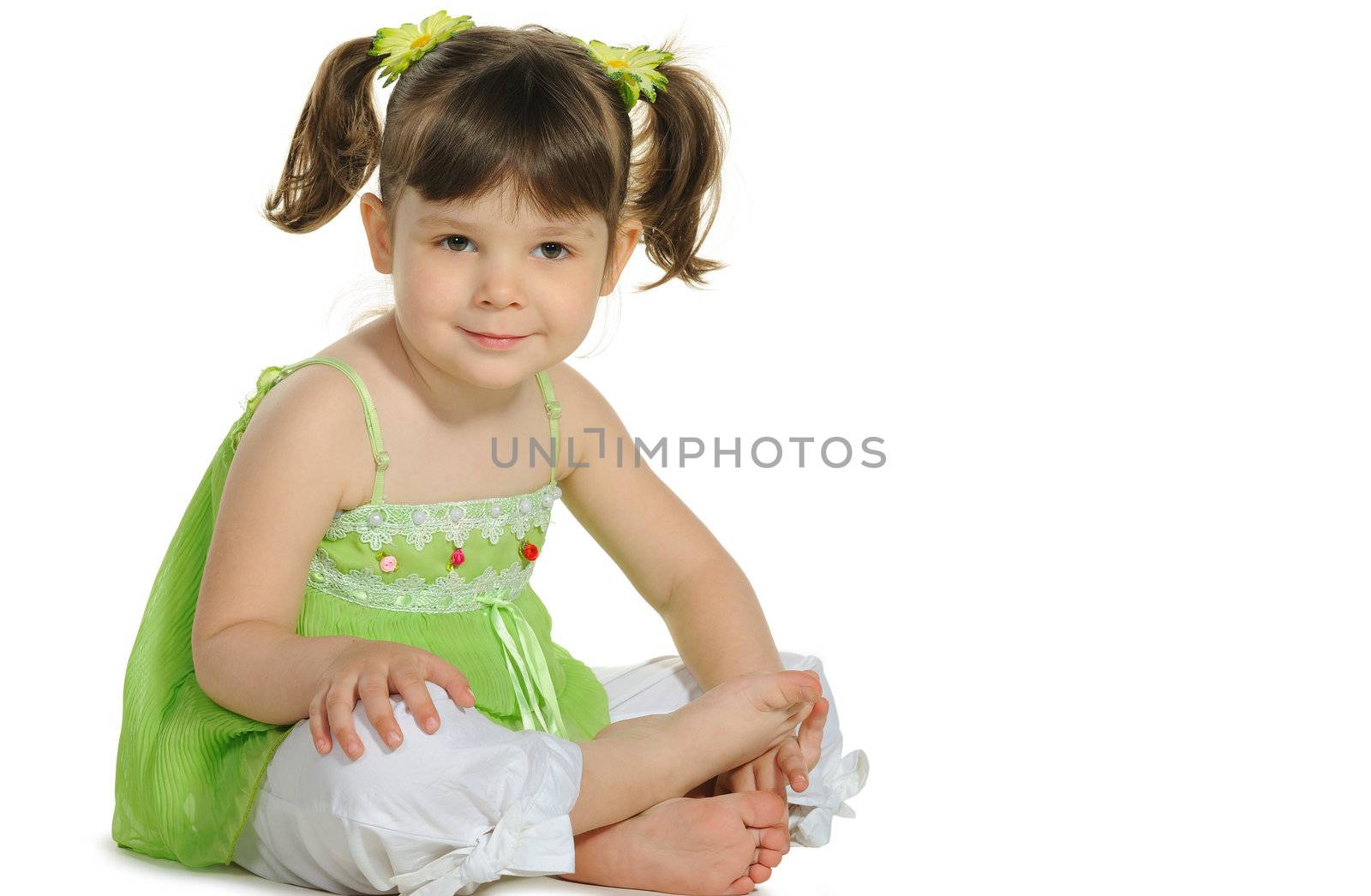 Pretty the little girl sits on the white. It is isolated on a white background