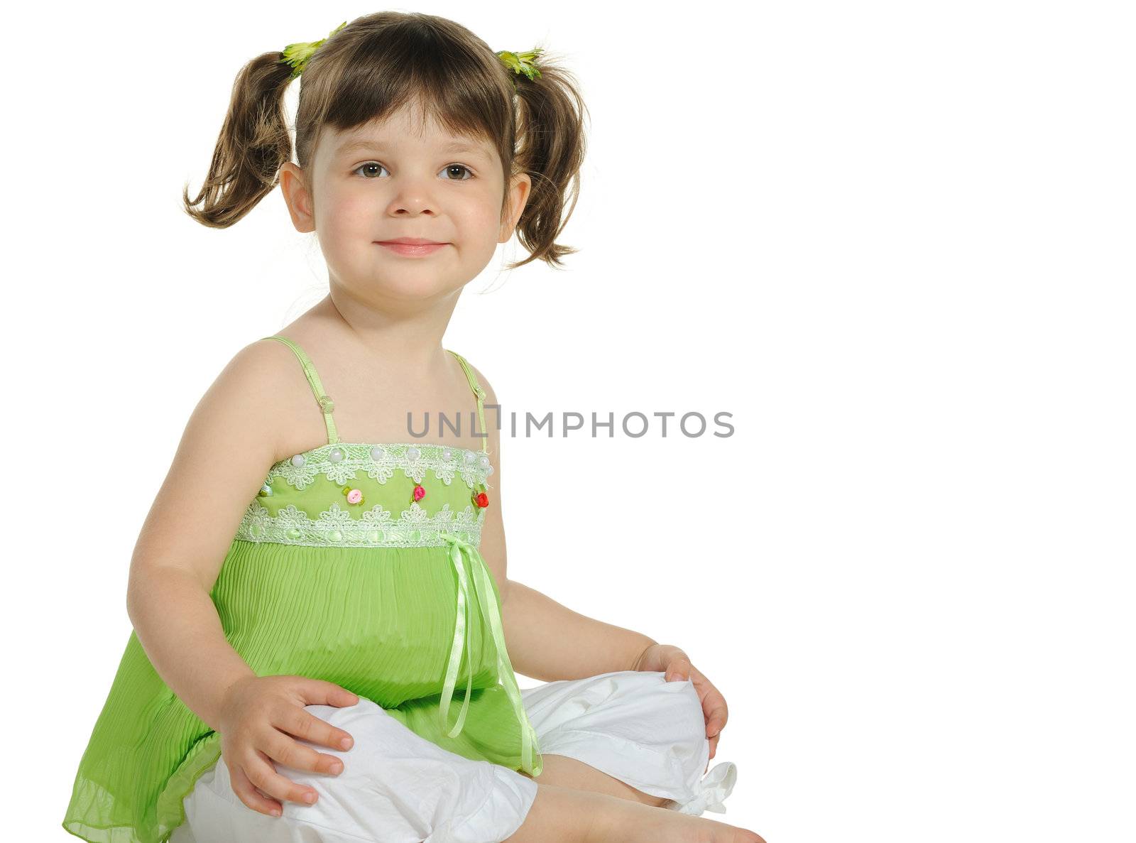 Pretty the little girl sits on the white. It is isolated on a white background