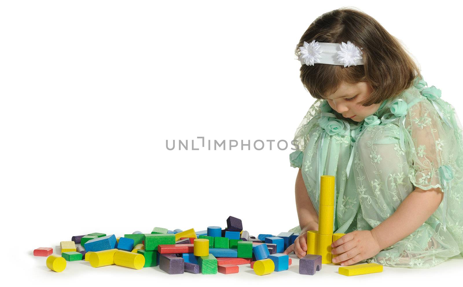 The lovely little girl plays colour wooden cubes. It is isolated on a white background