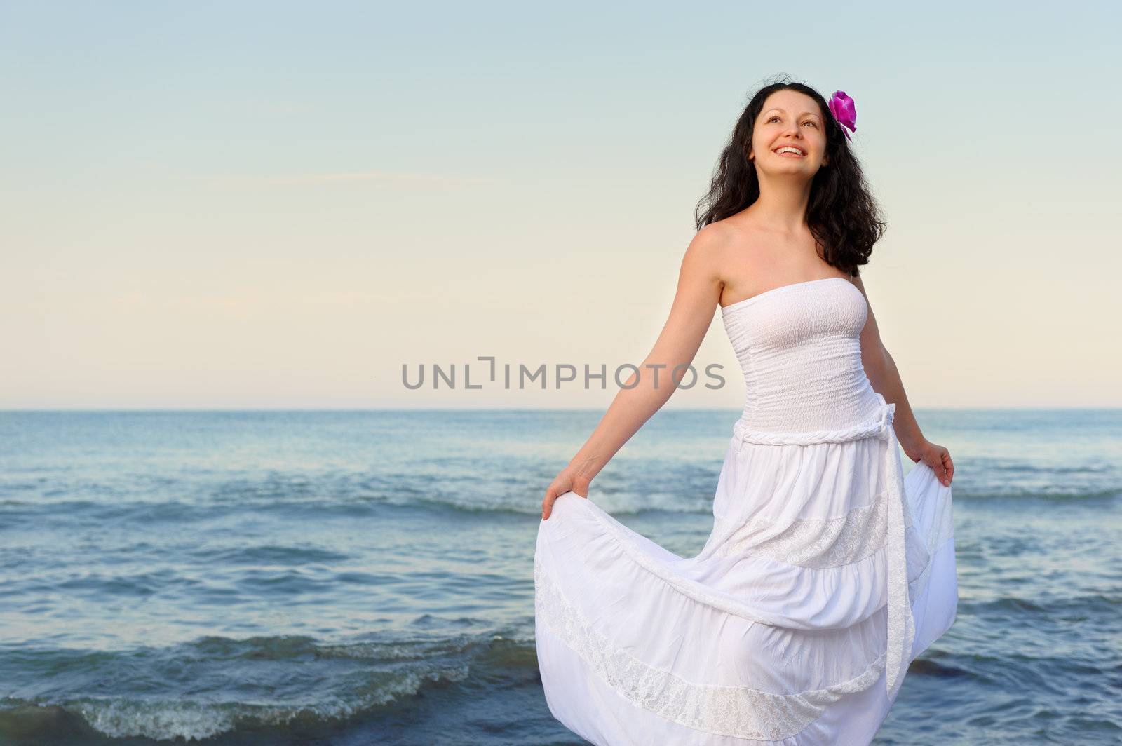 The woman in a white sundress on seacoast. A picturesque landscape